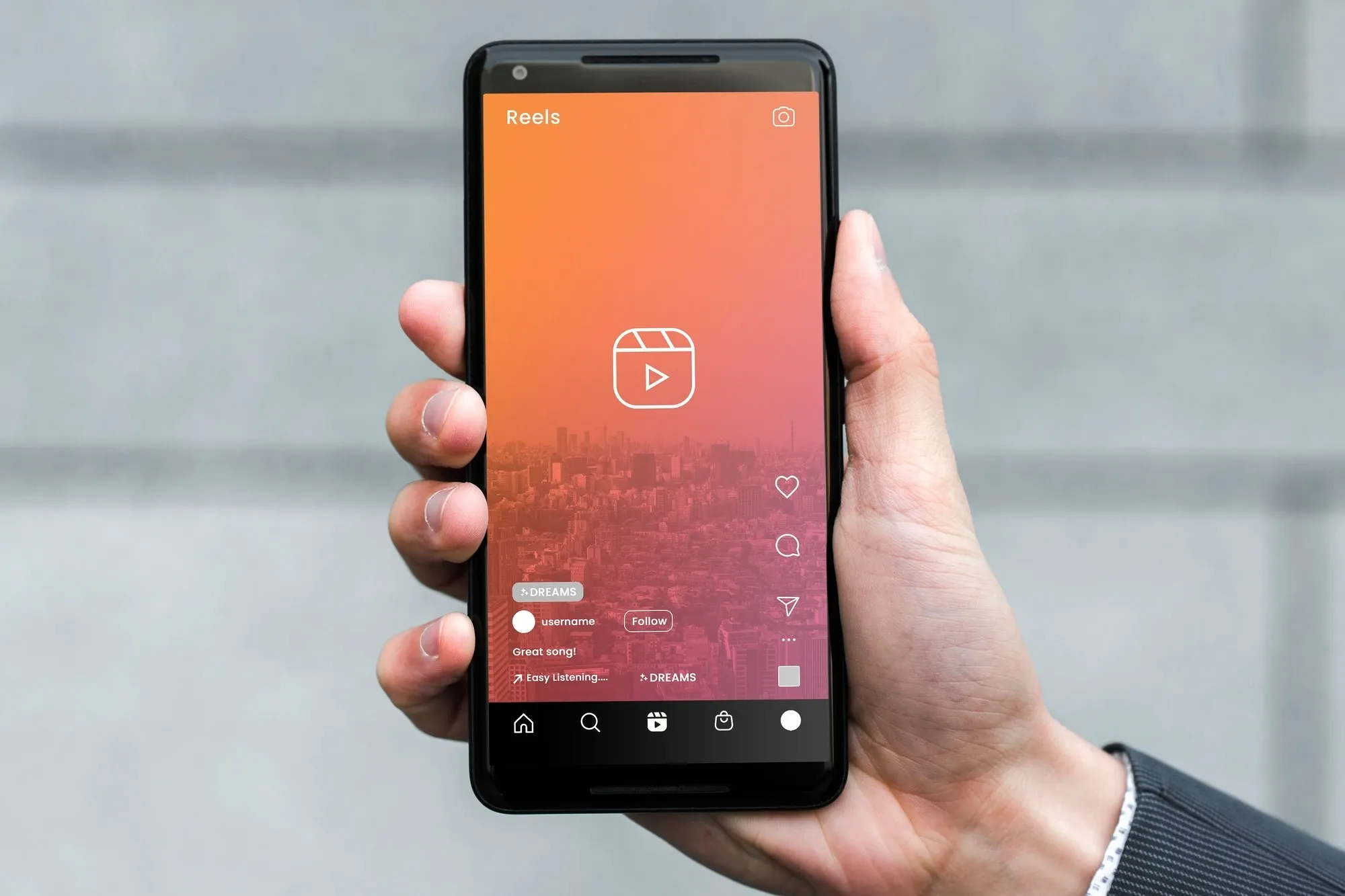 Hand holding a smartphone showing a social media app interface with a video reel feature.